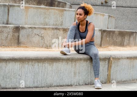 Frau, die vor dem Training Schnürsenkel in Sportschuhen bindet Stockfoto