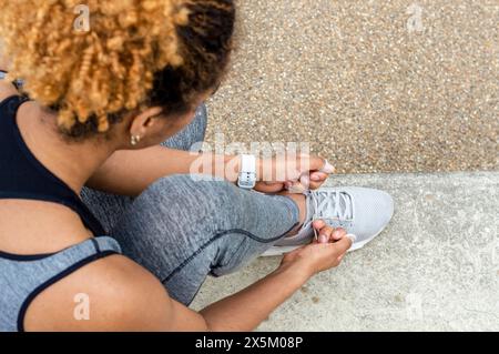 Frau, die Schnürsenkel bindet Stockfoto