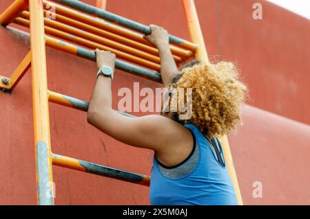 Sportliche, junge Frau, Kletterleiter Stockfoto