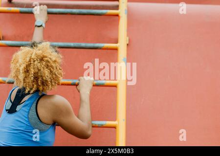 Sportliche, junge Frau, Kletterleiter Stockfoto