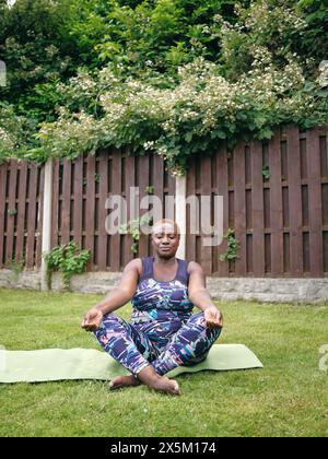 Frau meditiert auf Yogamatte im Garten Stockfoto