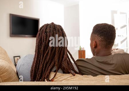 Geschwister sitzen auf dem Sofa vor dem Fernseher Stockfoto