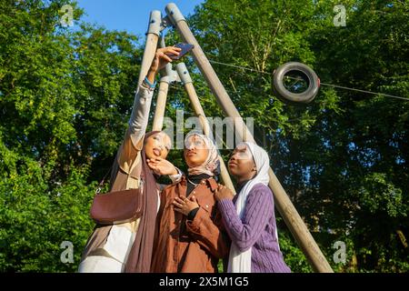 Großbritannien, London, drei junge Frauen in Hijabs machen Selfie im Park Stockfoto