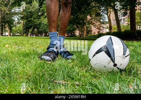 USA, Fußball und bemannte Beine auf dem Rasen im Park Stockfoto