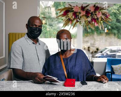 Großbritannien, Porträt eines älteren Paares in Masken an der Hotelrezeption Stockfoto