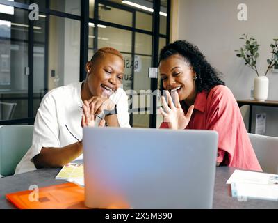 Zwei Frauen winken im Büro dem Laptop zu Stockfoto
