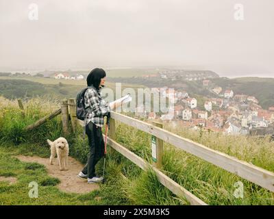 UK, weibliche Wanderer mit Hund, der sich Karte in der Landschaft ansieht Stockfoto