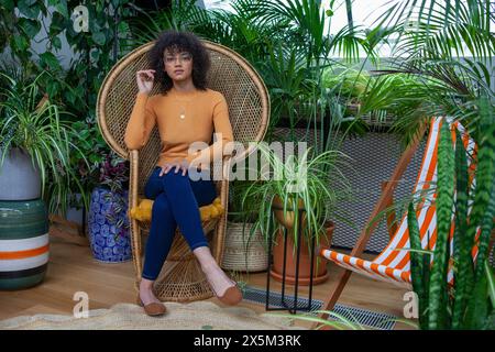 Porträt einer Frau, die im tropischen Rattansessel sitzt Stockfoto