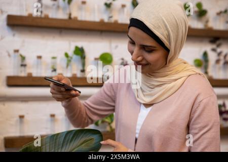 Frau mit Kopftuch, die Bananenblatt mit Smartphone fotografiert Stockfoto