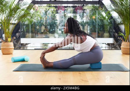 Frau erstreckt sich auf Yoga-Matte Stockfoto