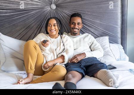 Frau und Mann mit Beinprothetik schauen im Schlafzimmer fern Stockfoto