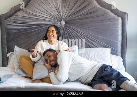 Frau und Mann mit Beinprothetik schauen im Schlafzimmer fern Stockfoto