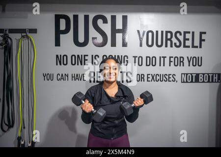 Frau, die im Fitnessstudio mit Hanteln trainiert Stockfoto