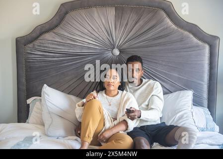 Frau und Mann mit Beinprothetik schauen im Schlafzimmer fern Stockfoto