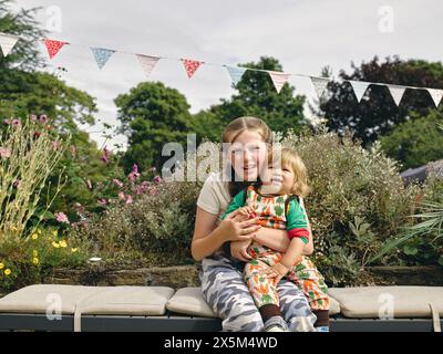 Porträt eines lächelnden Mädchens, das den kleinen Bruder hält Stockfoto