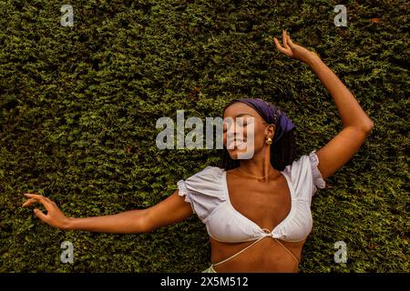 Porträt einer jungen Frau, die sich auf Evergreens stützt Stockfoto