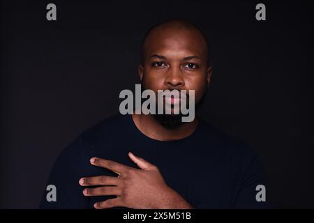 Studio-Porträt eines jungen Mannes auf schwarzem Hintergrund Stockfoto