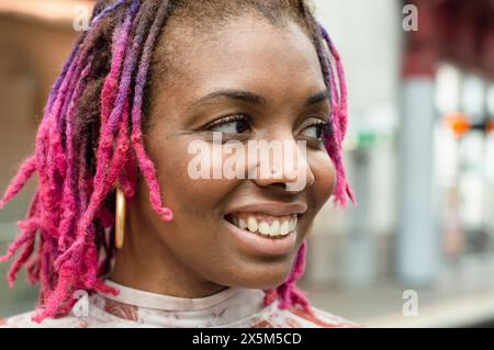 Nahaufnahme einer lächelnden Frau mit bunten Dreadlocks Stockfoto