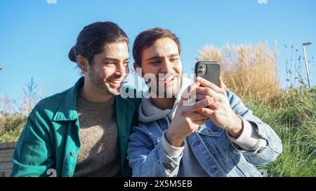 Lächelndes schwules Paar, das sich draußen selbst macht Stockfoto