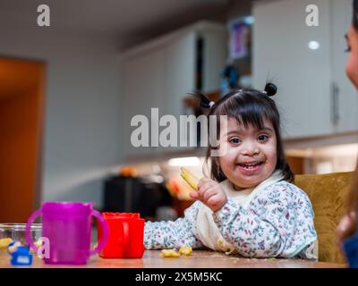 Porträt eines Mädchens mit Down-Syndrom beim Essen am Tisch Stockfoto