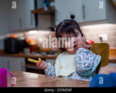 Porträt eines Mädchens mit Down-Syndrom beim Essen am Tisch Stockfoto
