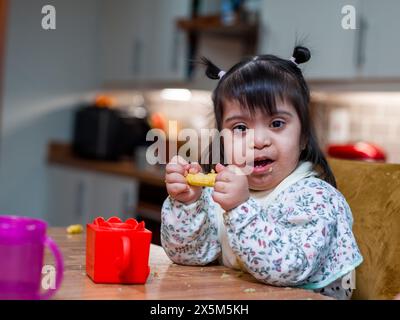 Porträt eines Mädchens mit Down-Syndrom beim Essen am Tisch Stockfoto