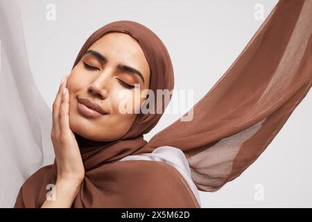 Studio-Porträt einer lächelnden Frau, die Brownhijab trägt Stockfoto