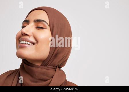 Studio-Porträt einer lächelnden Frau, die Brownhijab trägt Stockfoto