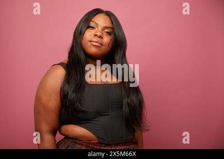 Studio-Porträt einer Frau in Übergröße vor rosa Hintergrund Stockfoto