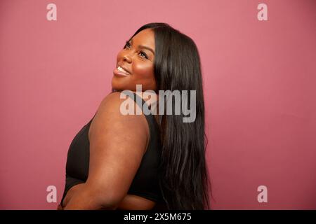 Studio-Aufnahme einer lächelnden, großen Frau vor rosafarbenem Hintergrund Stockfoto