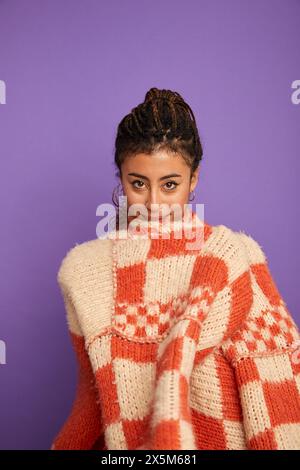Porträt einer Frau in weißem und rotem Pullover vor violettem Hintergrund Stockfoto
