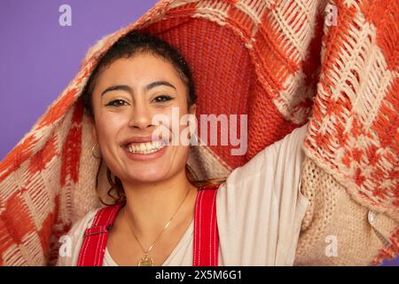 Studio-Porträt einer lächelnden Frau, die einen Pullover über dem Kopf hält Stockfoto