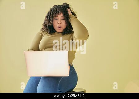 Studio-Aufnahme einer überraschten jungen Frau, die auf Laptop aussieht Stockfoto