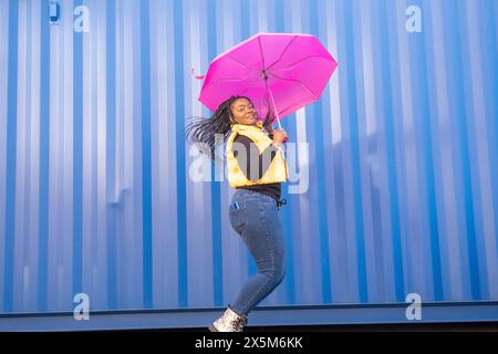 Großbritannien, South Yorkshire, Porträt einer Frau mit geflochtenen Haaren und rosa Regenschirm Stockfoto