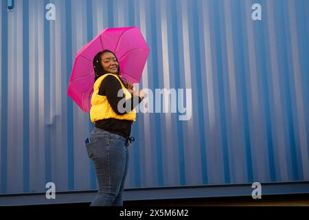 Großbritannien, South Yorkshire, Porträt einer Frau mit geflochtenen Haaren und rosa Regenschirm Stockfoto