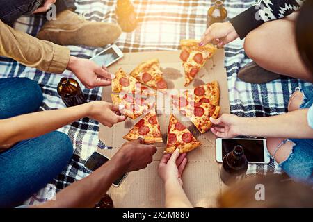 Hände, Freunde und Pizza im Freien für Picknicks, während Sie abhängen, chillen und sich mit Getränken verbinden. Oben, Hunger und Leute mit Fast Food Stockfoto