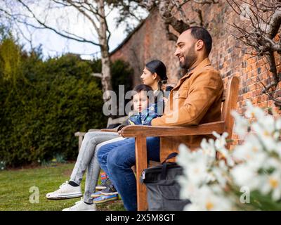 Eltern mit Sohn, der auf der Parkbank sitzt Stockfoto