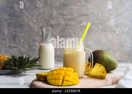Gesunder Mango- und Ananas-Smoothie in einem Glas auf grauem Hintergrund Stockfoto