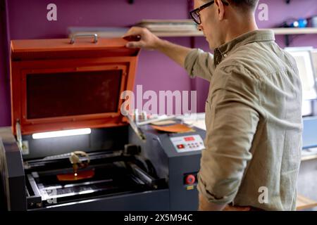 Professionelle Handwerker machen hochwertige Muster auf Lasergravurgeräten, Werkzeugen und Nahaufnahmen von hinten. Kopierraum. Hobby, Dekoration, Kunst. Kreativität Stockfoto