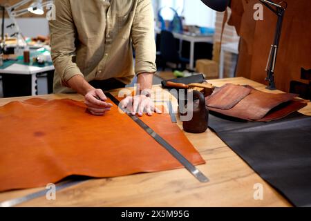 Erfahrener Schneiderschuster, der mit Textil in der Werkstatt arbeitet. Nahaufnahme zugeschnittener Schuss, Beruf, Beruf. Zinsen Stockfoto