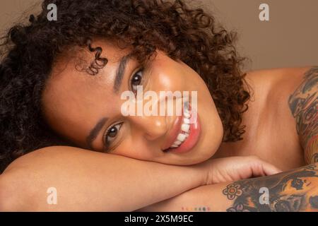 Studio-Porträt einer lächelnden Frau mit lockigem Haar Stockfoto