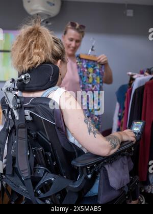 Assistentin, die einer Frau im Rollstuhl hilft, Kleidung auszusuchen Stockfoto