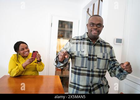 Lächelnde Mutter, die einen erwachsenen Sohn mit Down-Syndrom aufzeichnet Stockfoto