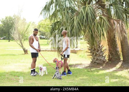 USA, Louisiana, Schwulenpaar mit Hunden auf dem Rasen im Park Stockfoto
