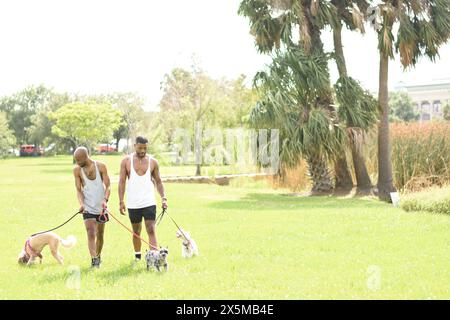 USA, Louisiana, Schwulenpaar mit Hunden auf dem Rasen im Park Stockfoto