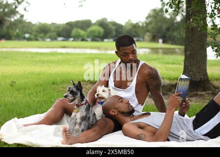 USA, Louisiana, Schwulenpaar mit Hunden, die sich auf dem Rasen im Park entspannen Stockfoto