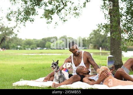 USA, Louisiana, Schwulenpaar mit Hunden, die sich auf dem Rasen im Park entspannen Stockfoto