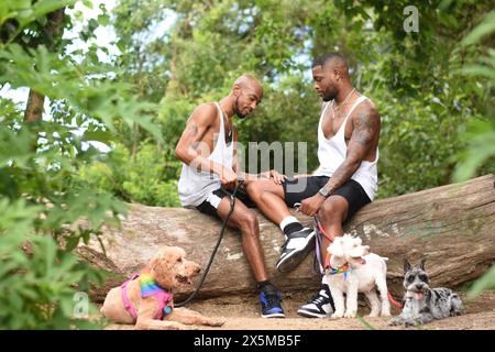 USA, Louisiana, Schwulenpaar mit Hunden, die im Wald sitzen Stockfoto