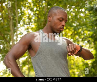 Sportlicher Mann, der im Park auf die Smart Watch schaut Stockfoto