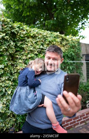 Ein lächelnder Mann macht Selfie mit der Tochter draußen Stockfoto